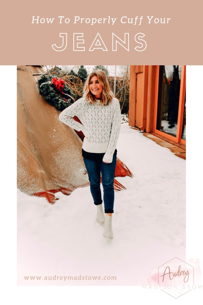 How To Cuff Women's Jeans featured by top US fashion blogger Audrey Madison Stowe; Woman standing in front of tepee wearing a sweater and jeans. 