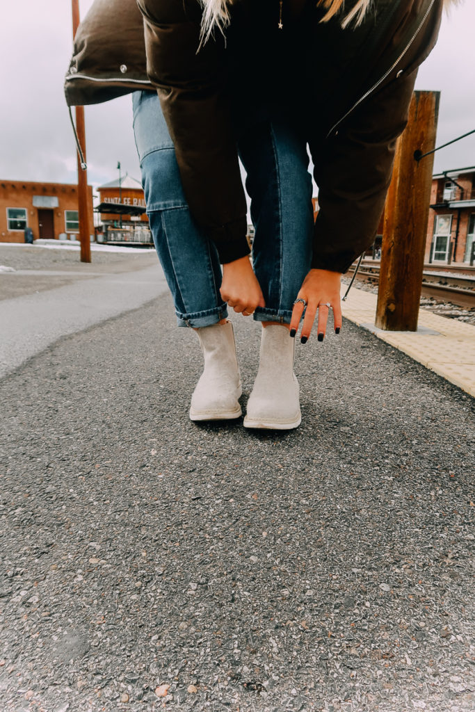 How To Cuff Women's Jeans featured by top US fashion blogger Audrey Madison Stowe; Woman fixing her jeans.