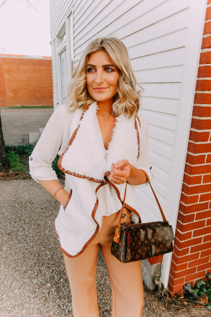 Ways To Wear a White Blouse featured by top US fashion blogger Audrey Madison Stowe; Image of woman wearing white blouse, shearling vest, work pants and nude heels.